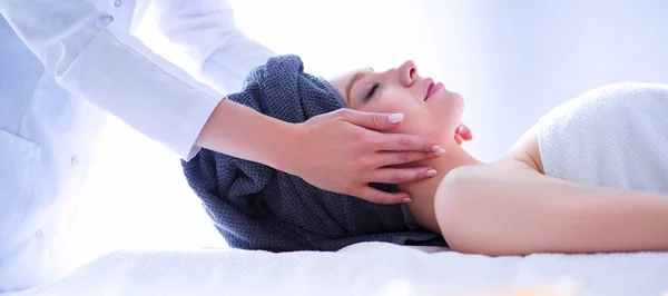 Jovem deitada em uma mesa de massagem, relaxando com os olhos fechados — Fotografia de Stock