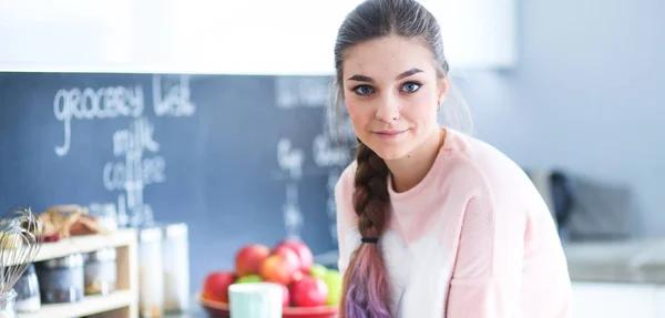 Giovane donna seduta sul tavolo in cucina . — Foto Stock