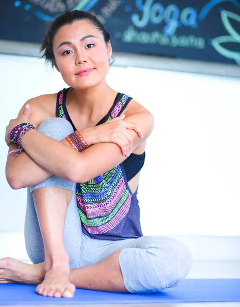 Portret van yoga vrouw zitten in yoga mat na training in yogastudio glimlachen. Yoga. Vrouw. — Stockfoto