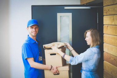 Mavi üniformalı gülümseyen kurye servis konseptine paket kutusu teslim eden teslimatçı. Mavi üniformalı gülümseyen teslimatçı.