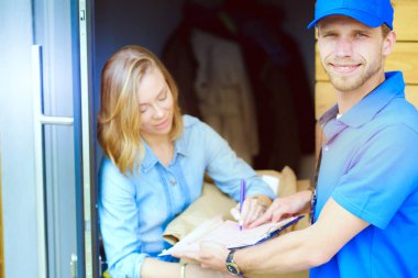 Mavi üniformalı gülümseyen kurye servis konseptine paket kutusu teslim eden teslimatçı. Mavi üniformalı gülümseyen teslimatçı.