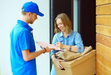 Mavi üniformalı gülümseyen kurye servis konseptine paket kutusu teslim eden teslimatçı. Mavi üniformalı gülümseyen teslimatçı.
