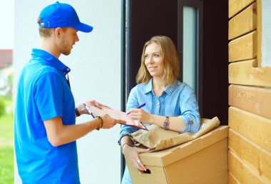 Mavi üniformalı gülümseyen kurye servis konseptine paket kutusu teslim eden teslimatçı. Mavi üniformalı gülümseyen teslimatçı.