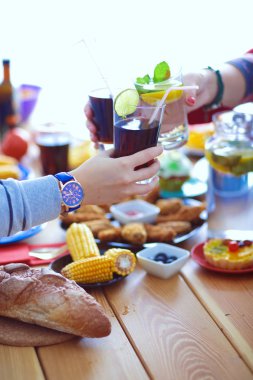 Ahşap masada otururken birlikte yemek yiyen bir grup insanın üst düzey görüntüsü. Masada yemek var. İnsanlar fast food yiyor..