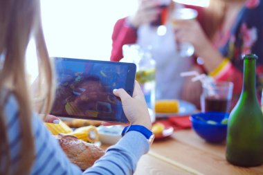 Ahşap masada otururken birlikte yemek yiyen bir grup insanın üst düzey görüntüsü. Masada yemek var. İnsanlar fast food yiyor..