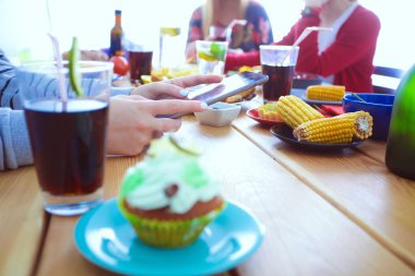Ahşap masada otururken birlikte yemek yiyen bir grup insanın üst düzey görüntüsü. Masada yemek var. İnsanlar fast food yiyor..
