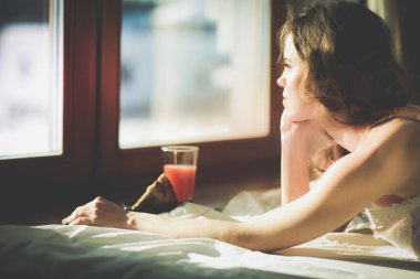 Pencere yakınındaki erken sabah yatakta yatan kadın.