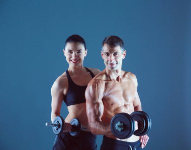 Atletik erkek ve kadın ile bir dumbells. Kişisel fitness eğitmeni. Kişisel eğitim.