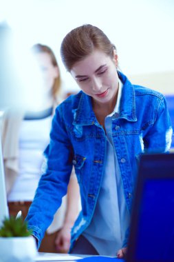 Masanın yanında duran iki genç kadın enstrüman, plan ve dizüstü bilgisayarla.