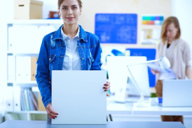 Masanın yanında duran iki genç kadın enstrüman, plan ve dizüstü bilgisayarla.