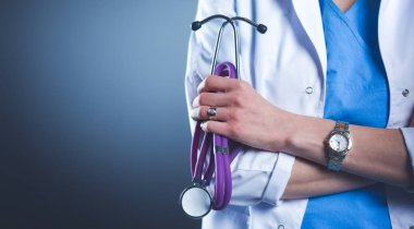 Elinde steteskop tutan genç bir kadın doktor portresi, siyah arka planda izole edilmiş.