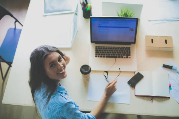 Giovane donna seduta al tavolo dell'ufficio, guardando lo schermo del computer portatile. Giovane donna — Foto Stock