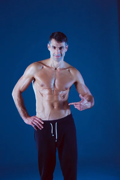 Muskelprotz. muskulöser Mann auf grauem Hintergrund, der Muskeln zeigt. Fitnesslehrer. Fitnessprofi. Training. Männerfitness. — Stockfoto
