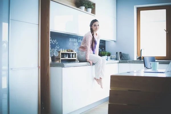 Mujer joven sentada en la mesa en la cocina . — Foto de Stock