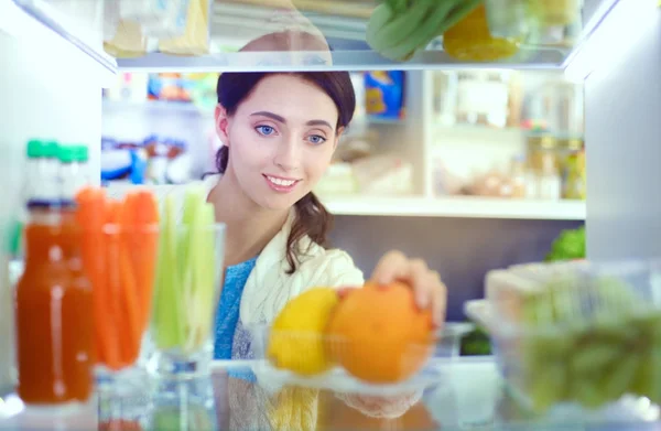 Retrato de fêmea em pé perto da geladeira aberta cheia de alimentos saudáveis, legumes e frutas. Retrato de fêmea — Fotografia de Stock