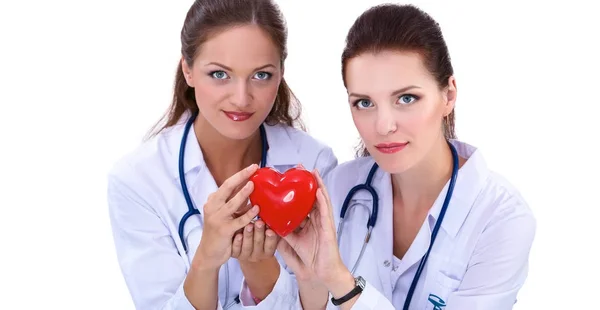 Две женщины-врача, держащие красное сердце, изолированные на белом фоне — стоковое фото