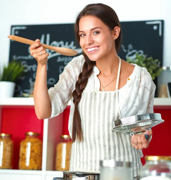 Ung kvinna står vid spisen i köket — Stockfoto