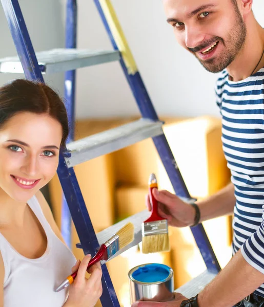Portrait heureux sourire jeune couple peinture mur intérieur de la maison neuve — Photo