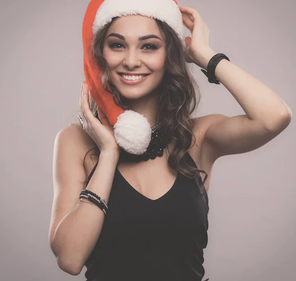Noel Baba şapkalı çekici gülümseyen kadın. Gri bir arka plan üzerinde izole. — Stok fotoğraf