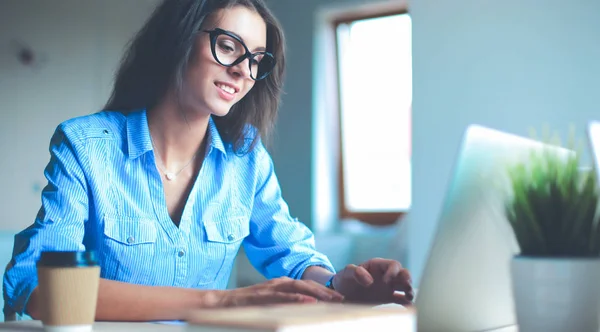 Giovane donna seduta al tavolo dell'ufficio, guardando lo schermo del computer portatile — Foto Stock