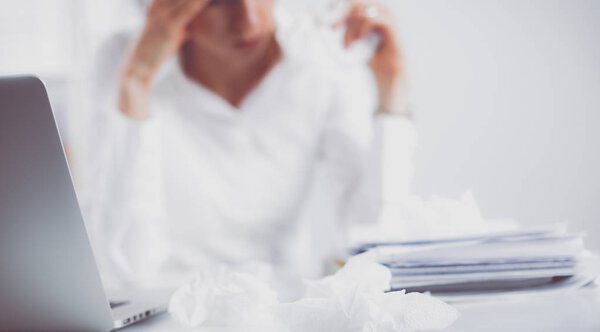 Стрессовая деловая женщина сидит за столом в офисе