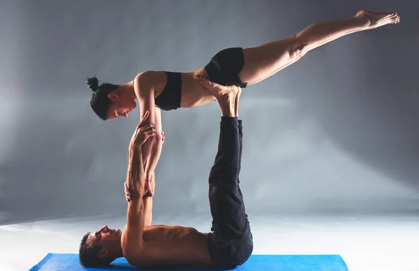 Cuplu tânăr practicând acro yoga pe mat în studio împreună — Fotografie, imagine de stoc