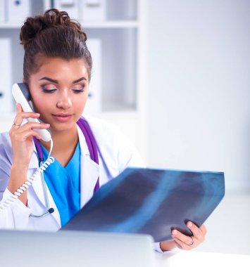 Masada oturan genç bayan doktor röntgen üzerinde çalışıyor.