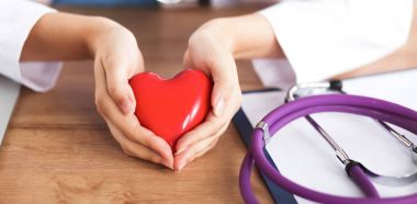 Kırmızı kalp sembollü genç doktor masasında tek başına oturuyor.