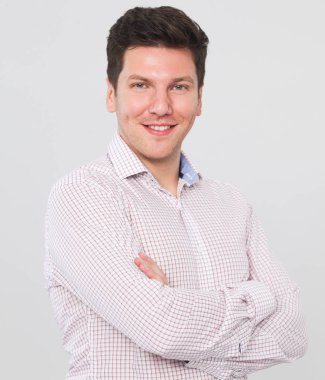 gri arka planı çapraz kollar ile ayakta, zeki genç bir adam portresi