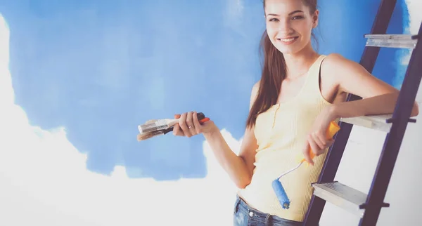 Feliz hermosa mujer joven haciendo pintura de pared, sentado en la escalera —  Fotos de Stock