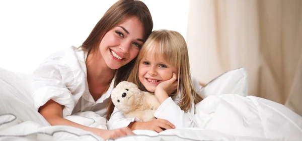 Woman and young girl lying in bed smiling — Stock Photo, Image