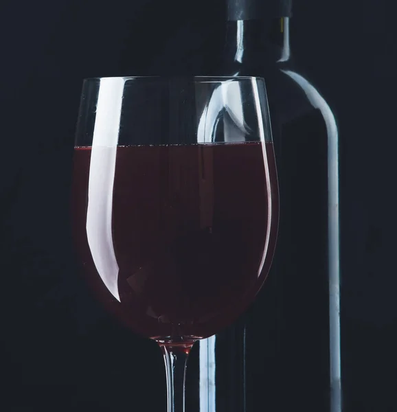 Copo de vinho e uma garrafa no fundo preto — Fotografia de Stock