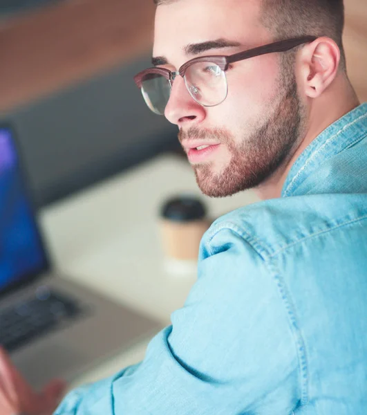 Jonge man met telefoon en werkt op de laptop — Stockfoto