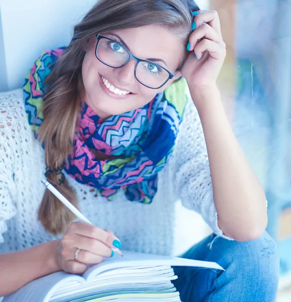 Young woman sitting at a desk among books — Stock Photo, Image