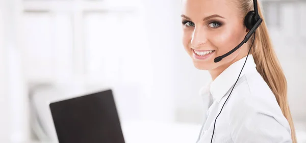 Retrato de mulher de negócios bonita trabalhando em sua mesa com fone de ouvido e laptop — Fotografia de Stock