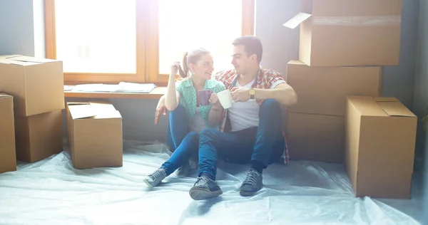 Par som flyttar i huset sitter på golvet — Stockfoto