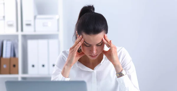 Porträtt av trött ung affärskvinna med laptop på kontoret — Stockfoto