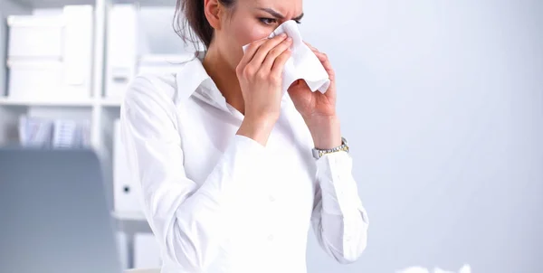 Junge Geschäftsfrau pustet sich die Nase, sitzt am Schreibtisch — Stockfoto