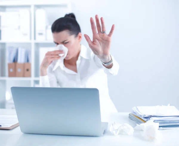 Jonge zakenvrouw snuit haar neus, zit aan het bureau — Stockfoto