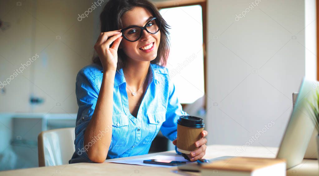 Young woman sitting in office table, looking at laptop computer screen