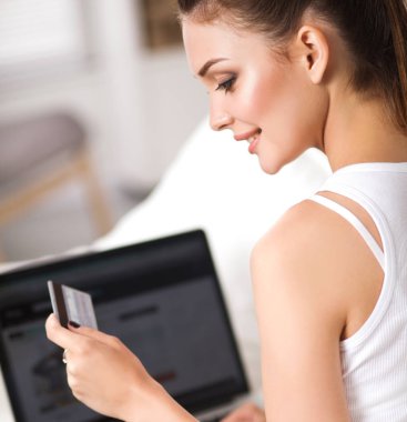 Kadın kredi kartı ve bilgisayarla online alışveriş yapıyor.