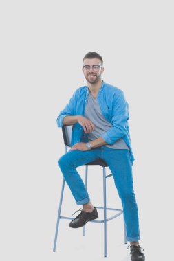 Beyaz arka plan üzerinde izole sandalye üzerinde oturan genç adam. Startupper. Genç girişimci.