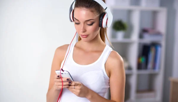 Kvinna med hörlurar lyssnar musik stående hemma — Stockfoto