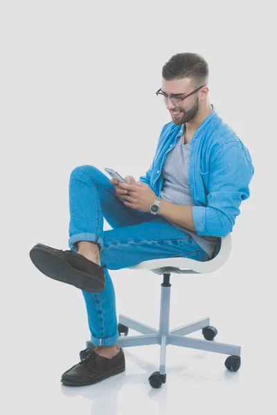 Mladý muž sedí na židli a pomocí mobilního telefonu. Startupper. Mladý podnikatel. — Stock fotografie