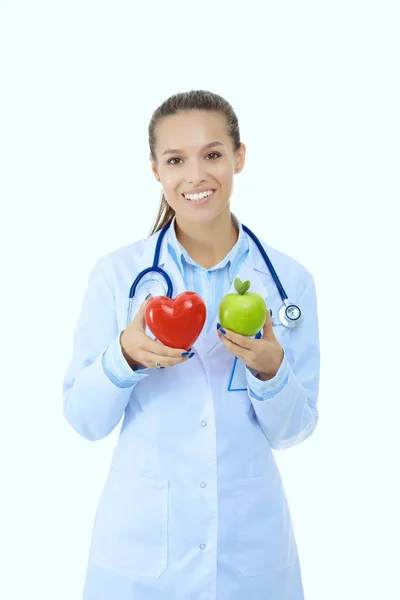 Krásná usměvavá doktorka držící červené srdce a zelené jablko. Ženský lékař — Stock fotografie