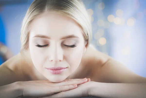 Mujer joven acostada en una mesa de masaje, relajándose con los ojos cerrados. Una mujer. Salón de spa — Foto de Stock