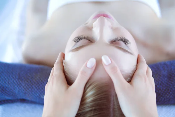 Mujer joven acostada en una mesa de masaje, relajándose con los ojos cerrados. Una mujer. Salón de spa — Foto de Stock