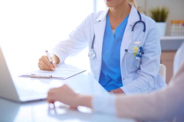 Masada oturan gülümseyen güzel genç bayan doktor.