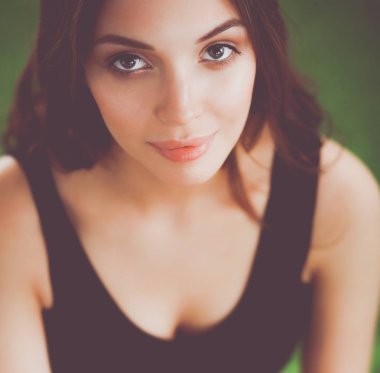 Yeşil çimenlerin üzerinde oturan genç fitness kız