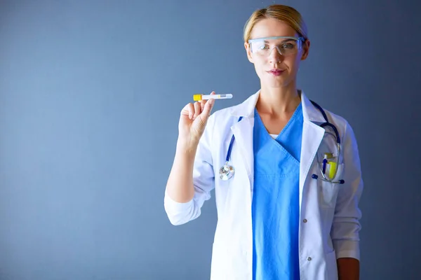 Medizinische oder wissenschaftliche Wissenschaftlerin oder Ärztin mit Blick auf ein Reagenzglas mit klarer Lösung in einem Labor oder Labor — Stockfoto
